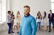 © Studio Romantic - Portrait of successful young Caucasian businessman forefront of happy multiracial employees clapping on background. Smiling motivated bearded man boss or executive with work team.