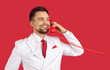 Smiling man in suit isolated on red studio background talk on landline phone. Happy handsome male in costume speak on corded telephone, have pleasant call. Communication concept.
