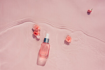 Wall Mural - Pink bottle with transparent serum, collagen, pink water background with flowers