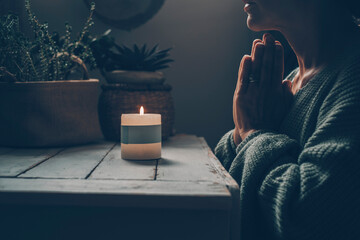 Wall Mural - Zen like lifestyle meditation in front of a candle light praying for one woman at home. Green mood color style. Mental health concept. Faith and religion. Candlelight in the dark indoor. Female people