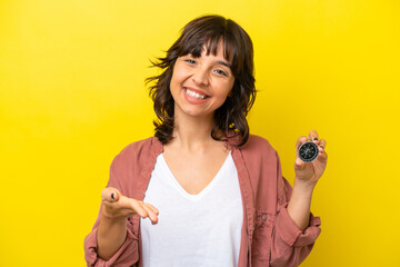 Wall Mural - Young latin woman holding compass isolated on yellow background shaking hands for closing a good deal