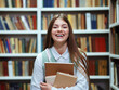 © yk_stock - Happy student with books laughing in library