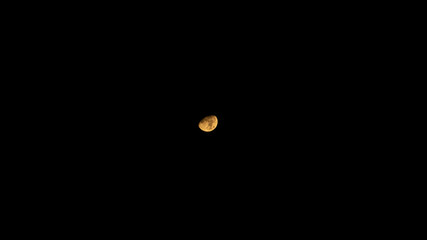 The orange moon in black sky. The half of orange moon on the clear black sky.