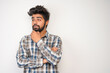 © Ashutosh khandale - young hispanic bearded man wearing plaid shirt over white background with positive expression, has broad interested smile. Look there, please.looking for something or found something