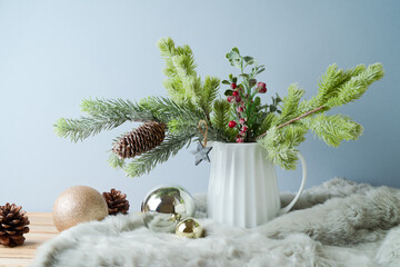 Wall Mural - Christmas table decoration with pine tree branches in vase and ornaments over bright background