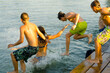 © Solid photos - Teenage boys and girls jumping into the water from the dock