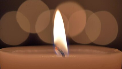 Sticker - Closeup shot of a burning orange flame on a candle on a bokeh background