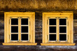 Wooden rustic window in small cottage house. Two transparent glass window black inside. Handmade brown frame. Wooden window background. Cottage house. Thatch roof vintage cabin wall.