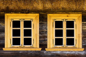 Wooden rustic window in small cottage house. Two transparent glass window black inside. Handmade brown frame. Wooden window background. Cottage house. Thatch roof vintage cabin wall.