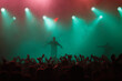 Rap singer performing on concert in music hall. Silhouette of rapper singing on stage in night club