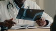 © Yuliia - Unrecognizable man doctor african radiologist surgeon therapist osteopath show x-ray scan result MRI tomography roentgen of broken bones joints to patient with trauma surgery consultation in hospital