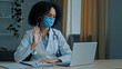 © Yuliia - Ethnic african woman doctor therapist cardiologist psychotherapist in medical mask write prescription diagnosis speaking in video chat calling patient distant online treatment during covid-19 epidemic