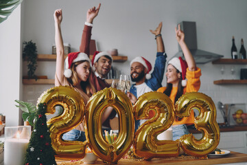 Wall Mural - Happy young people celebrating New Year with gold colored decoration on foreground