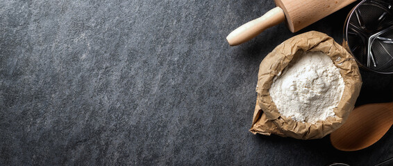Poster - Paper bag of flour on dark background with copy space top view. Bakery background