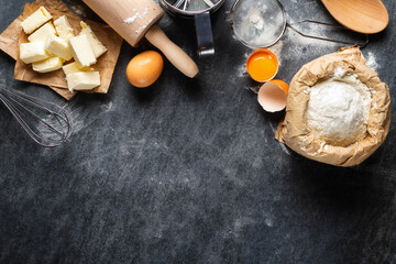 Poster - Ingredients for cooking baking dough, paper bag with flour, eggs, butter, rolling pin and sieve on dark background with copy space top view.  Bakery background