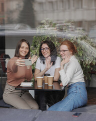 three female friends are talking in a coffee shop and drinking tea, moral support and caring friendship. mental health, group therapy and communication with friends and colleagues. happy or sad women