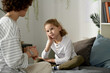 © Mediaphotos - Little boy having serious conversation with his mom while sitting on bed in his bedroom