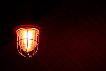 An Old Signal Lamp With Red Lighting Hangs On The Ceiling Of A Room, A Building. The Lantern Creates A Semi-darkness