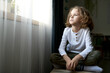 © Mediaphotos - Pensive little boy sitting in his room and looking at window with thoughtful sight