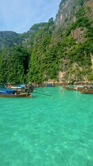 Wall Mural - Thai women in front of a Longtail boat at Pileh Lagoon Koh Phi Phi Thailand with the green emerald ocean at Koh Phi Phi Thailand, women in front of a longtail boat