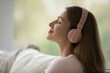 Side view face serene woman wear headphones enjoy music, feel carefree looks peaceful, close up. Weekend leisure and pastime using modern technology, hobby at home, listen mantras for deep inner peace