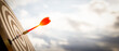 © kunakorn - Close up shot red darts arrows in the target  of dartboard center on dark blue sky background. Business target or goal success and winner concept.