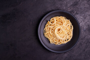 Canvas Print - Delicious spaghetti pasta with prawns and cheese served in a black bowl on a black background table Italian recipe, tomato sauce, vegetables, and spices top view with copy space