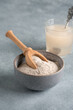 Psyllium husk powder in bowl and glass with of water soluble fiber for intestinal, gray background. Gluten free diet concept. Side view, selective focus, vertical