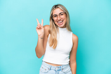 Wall Mural - Young caucasian woman isolated on blue background smiling and showing victory sign