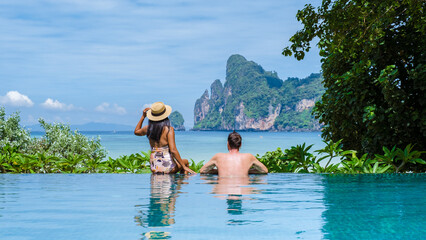 Wall Mural - couple of caucasian men and Thai women at the infinity pool looking out over the beach of Koh Phi Phi Thailand