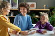© Mediaphotos - Happy mother laughing together with her children while they sitting at table and reading book