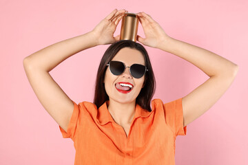 Sticker - Beautiful young woman holding tin can with beverage on pink background