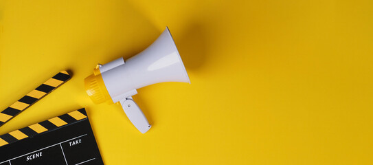 Clapper board and yellow megaphone on yellow background..