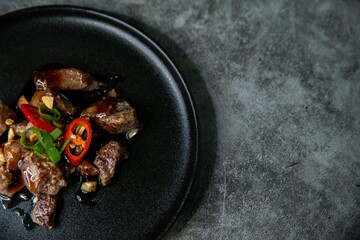 Poster - Korean Galbi Jjim, braised short ribs with spring onion and pepper in black plate on dark background