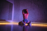 Fototapeta Uliczki - Photo of a professional twerk dancer dancing on the floor in a dance hall with pink light.Photo of a professional twerk dancer dancing on the floor in a dance hall with pink light.