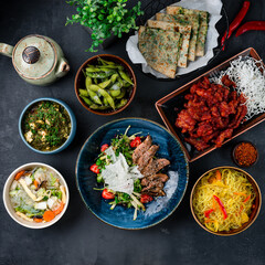 Wall Mural - Asian banquet sweet and sour chicken, chicken noodle soup with shiitake mushrooms, rice noodles with vegetables, duck fillet salad, beans, homemade cheese, cheese and spinach tortillas.