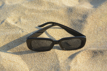 Canvas Print - Stylish sunglasses on sandy beach, closeup. Space for text