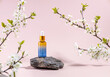 bottle of serum on a podium made of stone and plum blossom branches on a beige background
