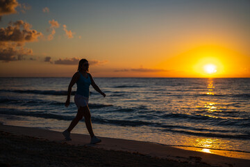 Wall Mural - Woman walking on sunny, tropical beach at daybreak
