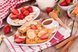 Fototapeta Uliczki - Waffles with strawberries, bananas and honey.