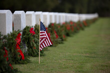 Laying Of Christmas Wreaths At National Cemetery With Red Ribbons And American Flag