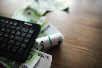 Wall Mural - Computer keyboard and a scattering of 100 euro bills on the table. The work of a programmer and blogger on the Internet.