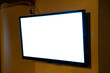 A flat TV set mounted on the wall of a room. Angled shot, blank cutout screen.
