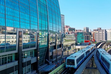 Wall Mural - View of a train traveling on elevated rails of Taipei Metro System by a modern building of glass curtain walls on a beautiful sunny day ~ View of MRT railways in Taipei, the capital city of Taiwan