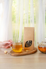 Organic tea branding and packaging mockup. Jasmine green tea in glass teapot on table. Hot tea is in the glass cups. Teapot and cup of tea with green tea on the table. Copy space.