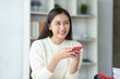 Beautiful young Asian woman using a smartphone transact on social media applications with a smiling face.
