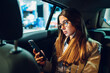 © Zamrznuti tonovi - Business woman using smartphone while sitting in a backseat of a car at night