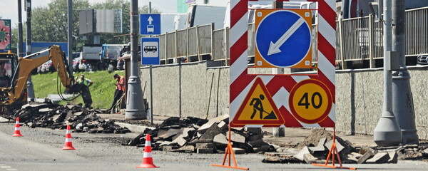 Road works - sign with speed limit 40 and direction arrow on roadside and excavator background