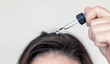 woman applying serum oil on wet hair with pipette or using white comb to disentangle isolated.healthy strong hair,growth stimulation stop fall shiny.top of head forehead lateral view.after pregnancy