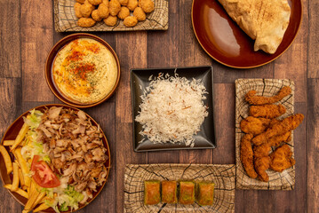 Wall Mural - Set of typical kebab restaurant recipes with a plate with meat and homemade potatoes, basmati rice, chicken strips, a plate of hummus with oil and paprika and baklava dessert